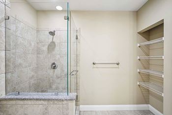 A walk-in shower with a glass door and a bench seat.